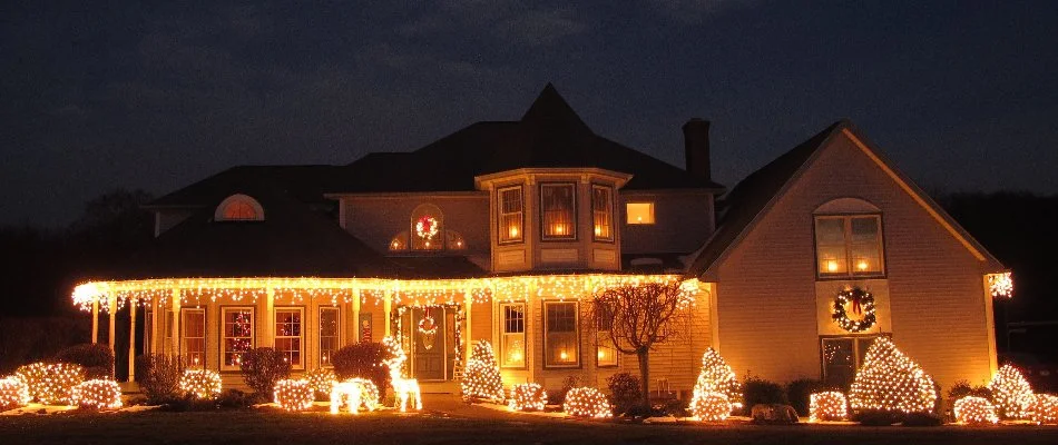 Warm white holiday lights on a house and shrubs in Huron, OH.
