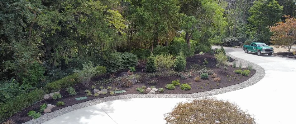 Mulched landscape bed in Avon, OH, along a driveway and wood line.